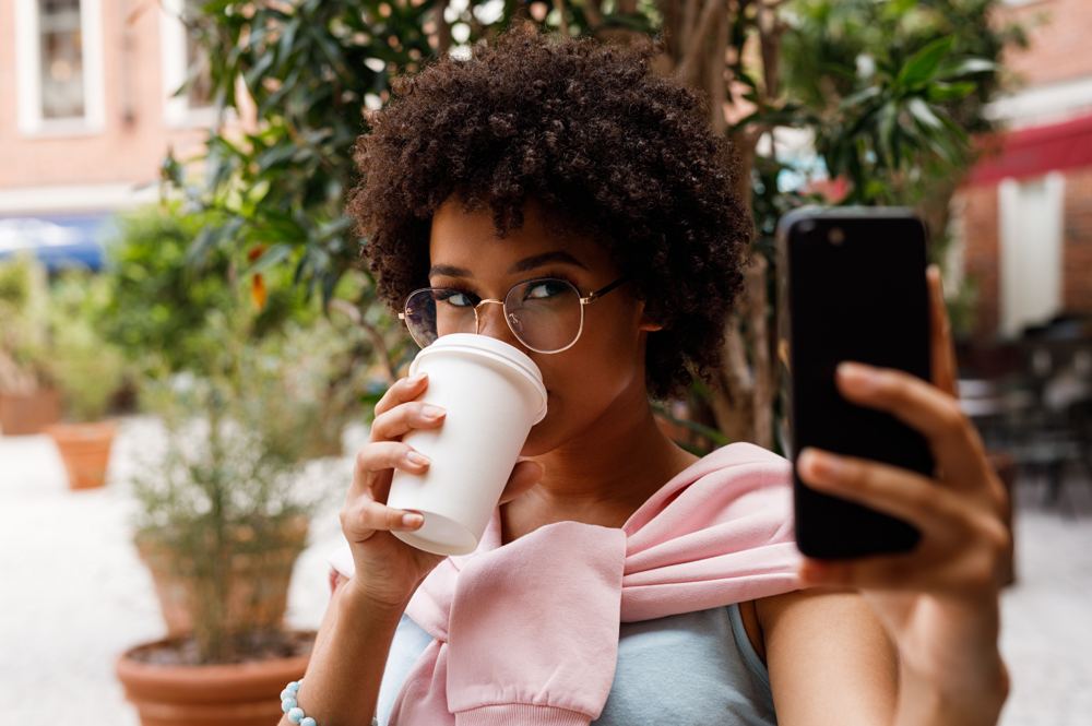 Mujer haciéndose un selfie con un café
